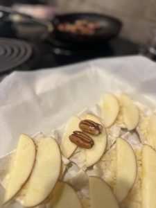 Shredded cheese, sliced apples, and pecan halves on raw puff pastry sheet